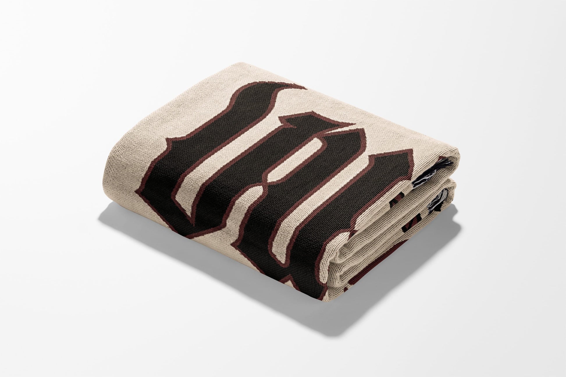 Folded tan blanket with large black gothic script initial "M".