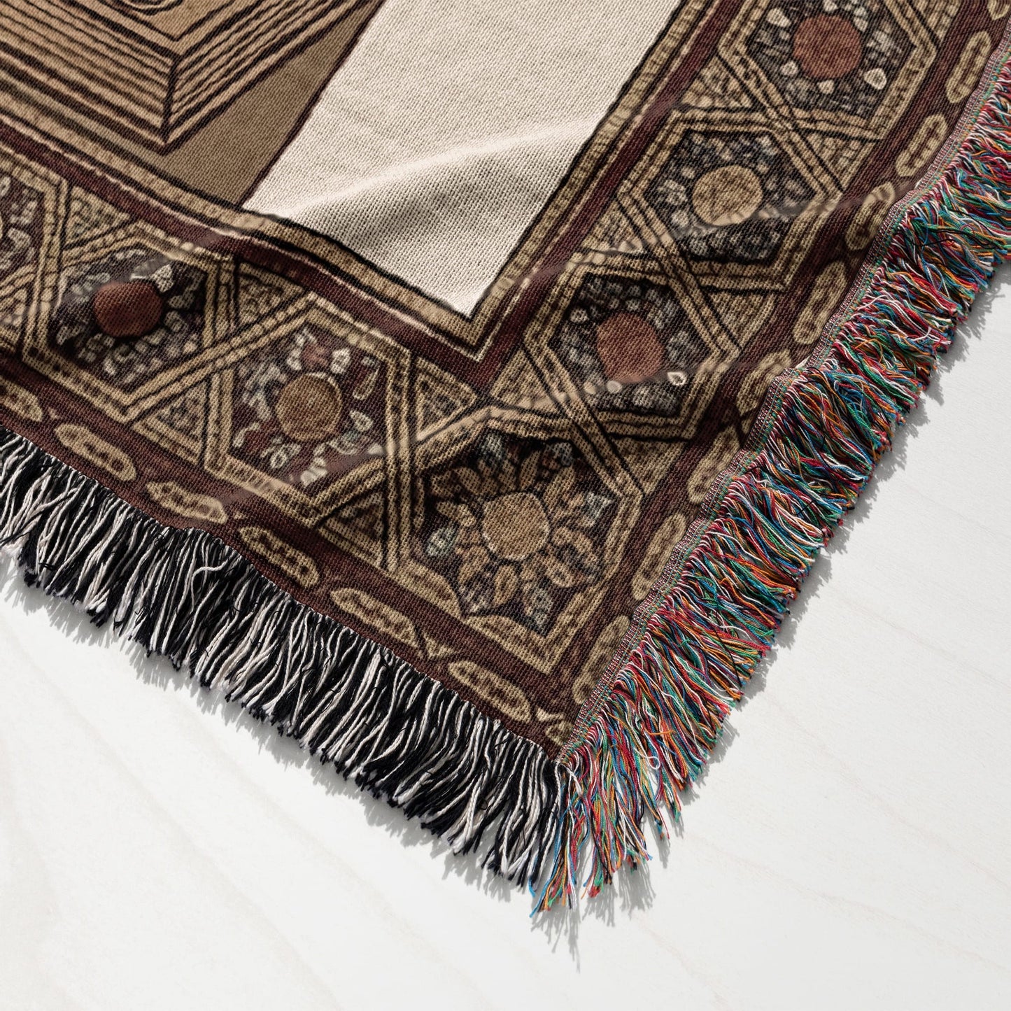 Woven throw blanket with geometric pattern and colorful fringe.