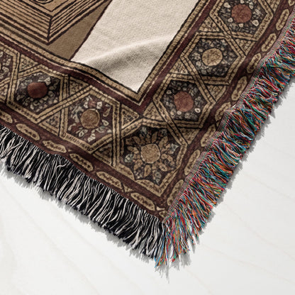 Woven throw blanket with geometric pattern and colorful fringe.