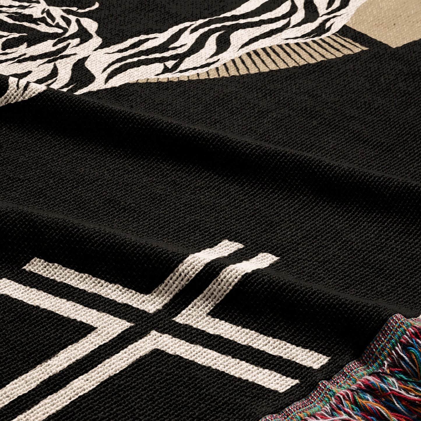 Black blanket with white geometric pattern and fringed edge.