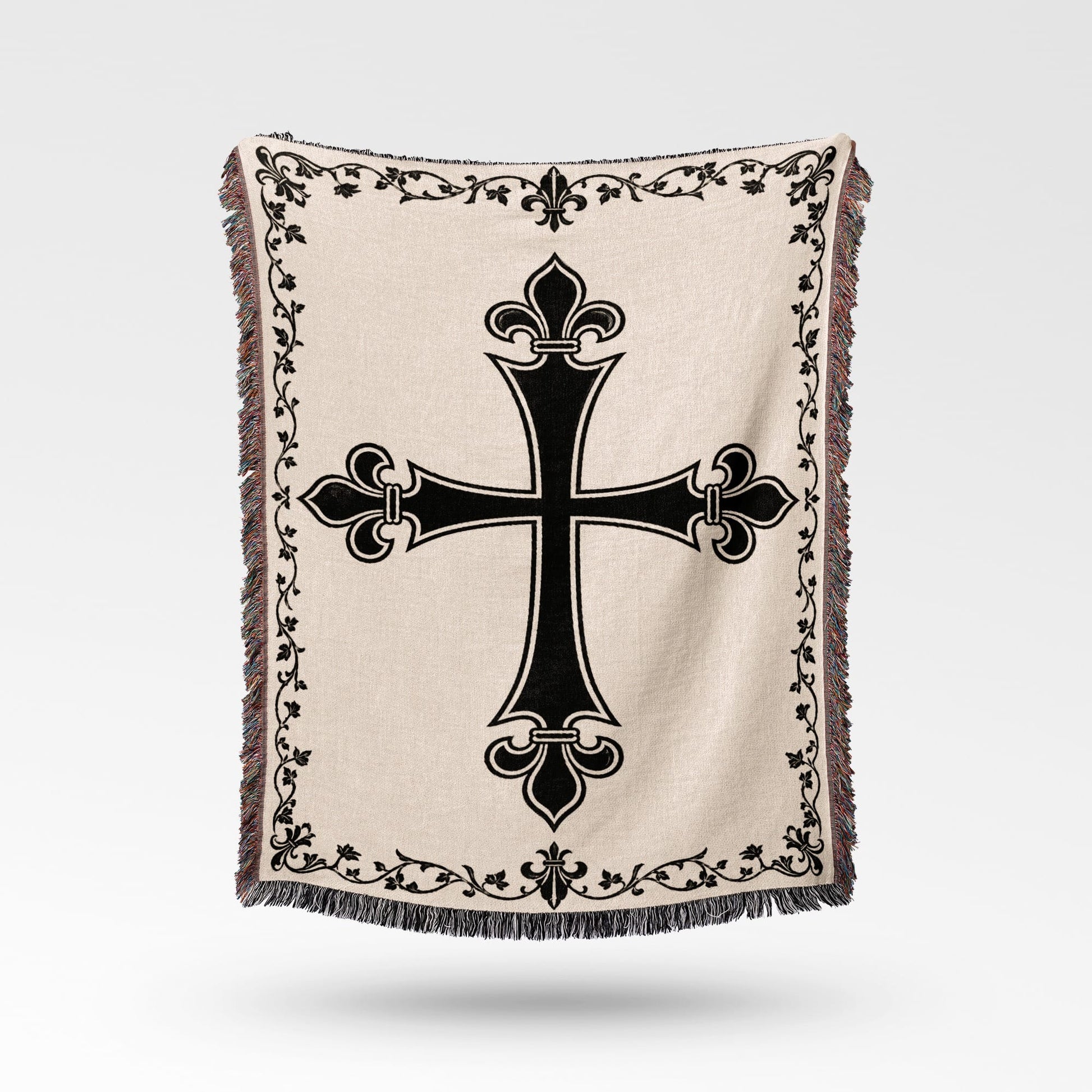 Beige woven throw blanket with a black fleur-de-lis cross design and ornate border.