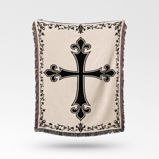 Beige woven throw blanket with a black fleur-de-lis cross design and ornate border.