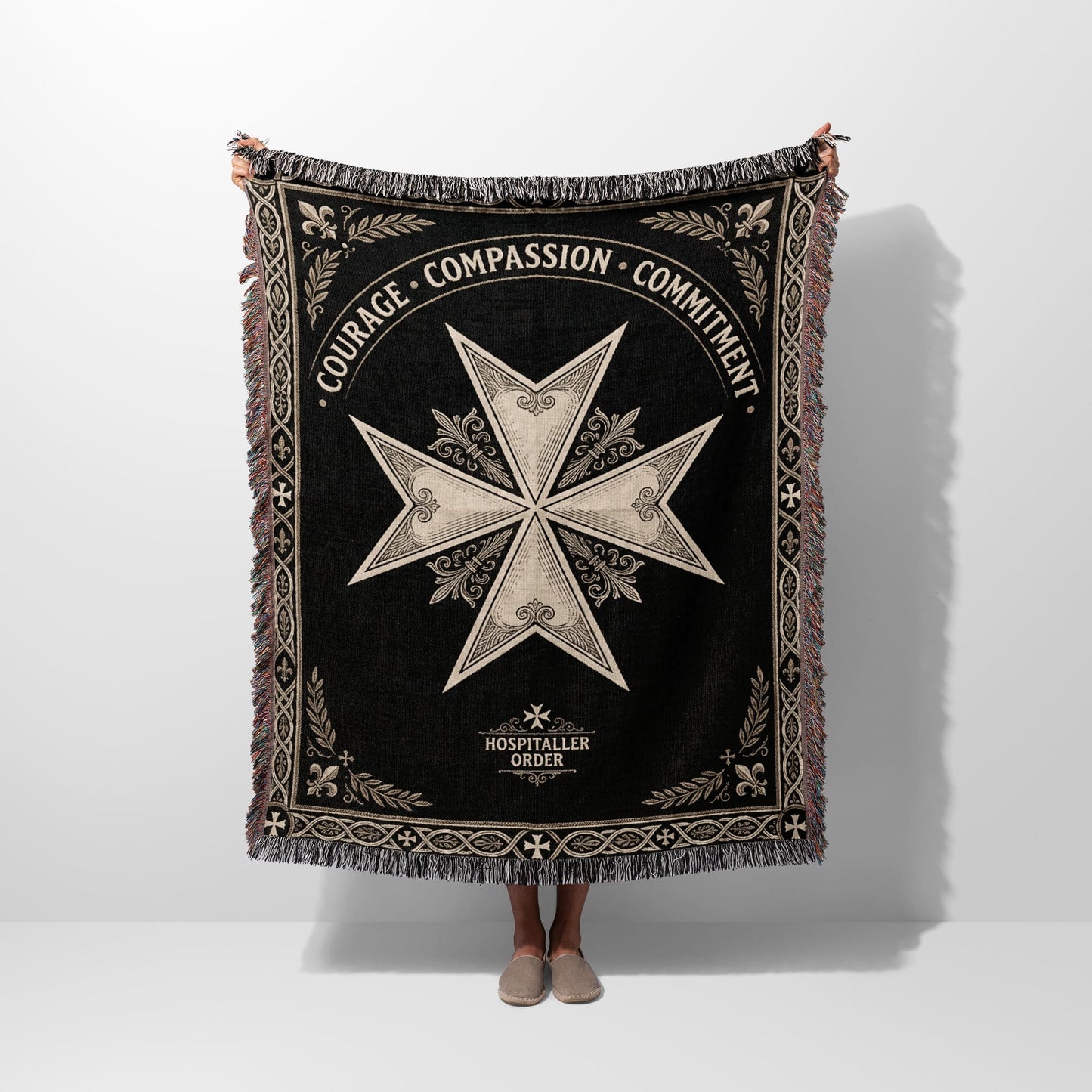 Black woven blanket with cross motif, "COURAGE COMPASSION COMMITMENT", and "HOSPITALLER ORDER".