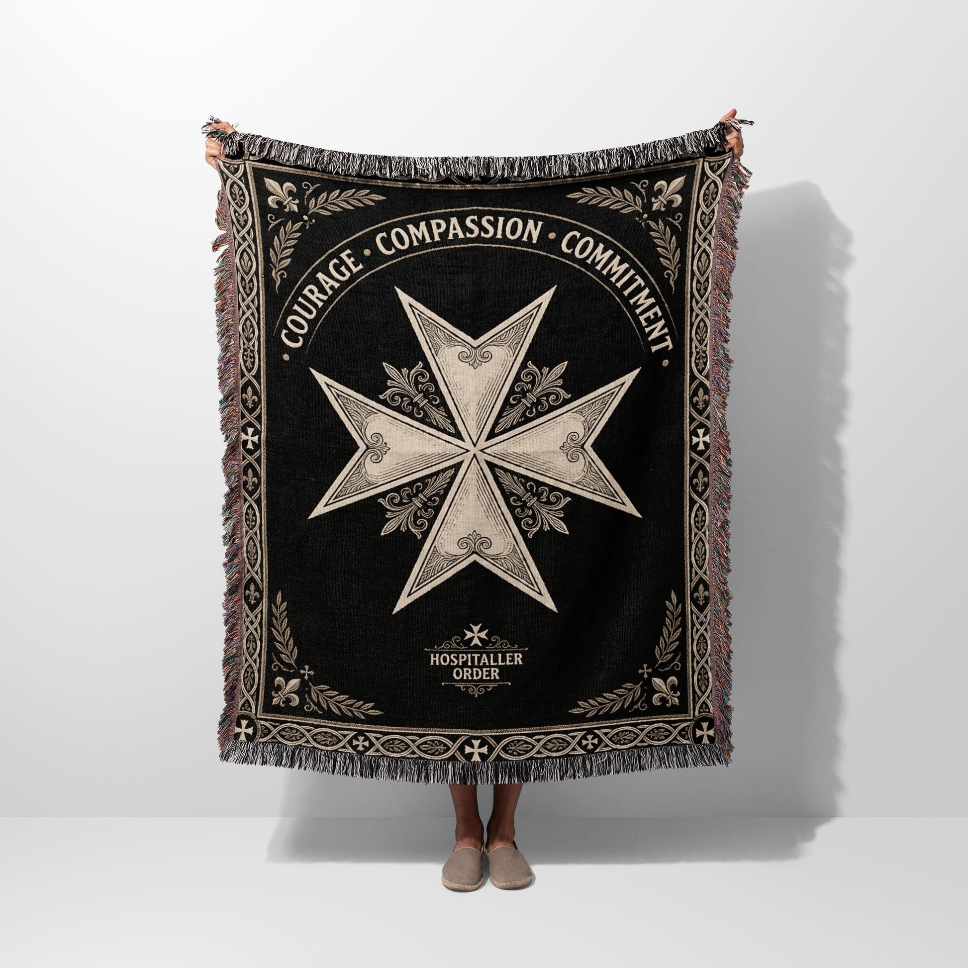 Black woven blanket with cross motif, "COURAGE COMPASSION COMMITMENT", and "HOSPITALLER ORDER".
