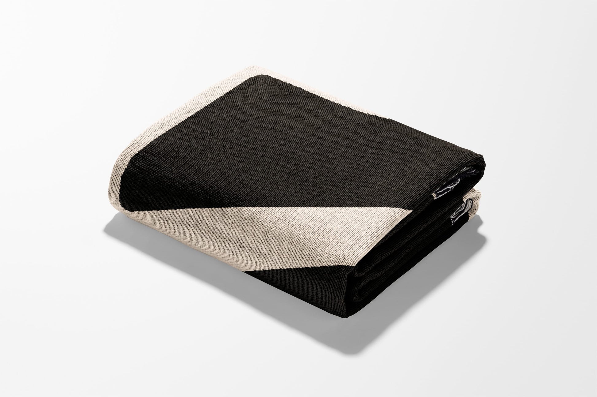 Black and beige striped woven throw blanket folded neatly on a white surface.