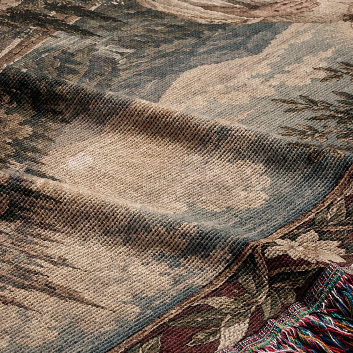 A woven blanket featuring a textured landscape pattern with muted tones of beige, green, and blue.