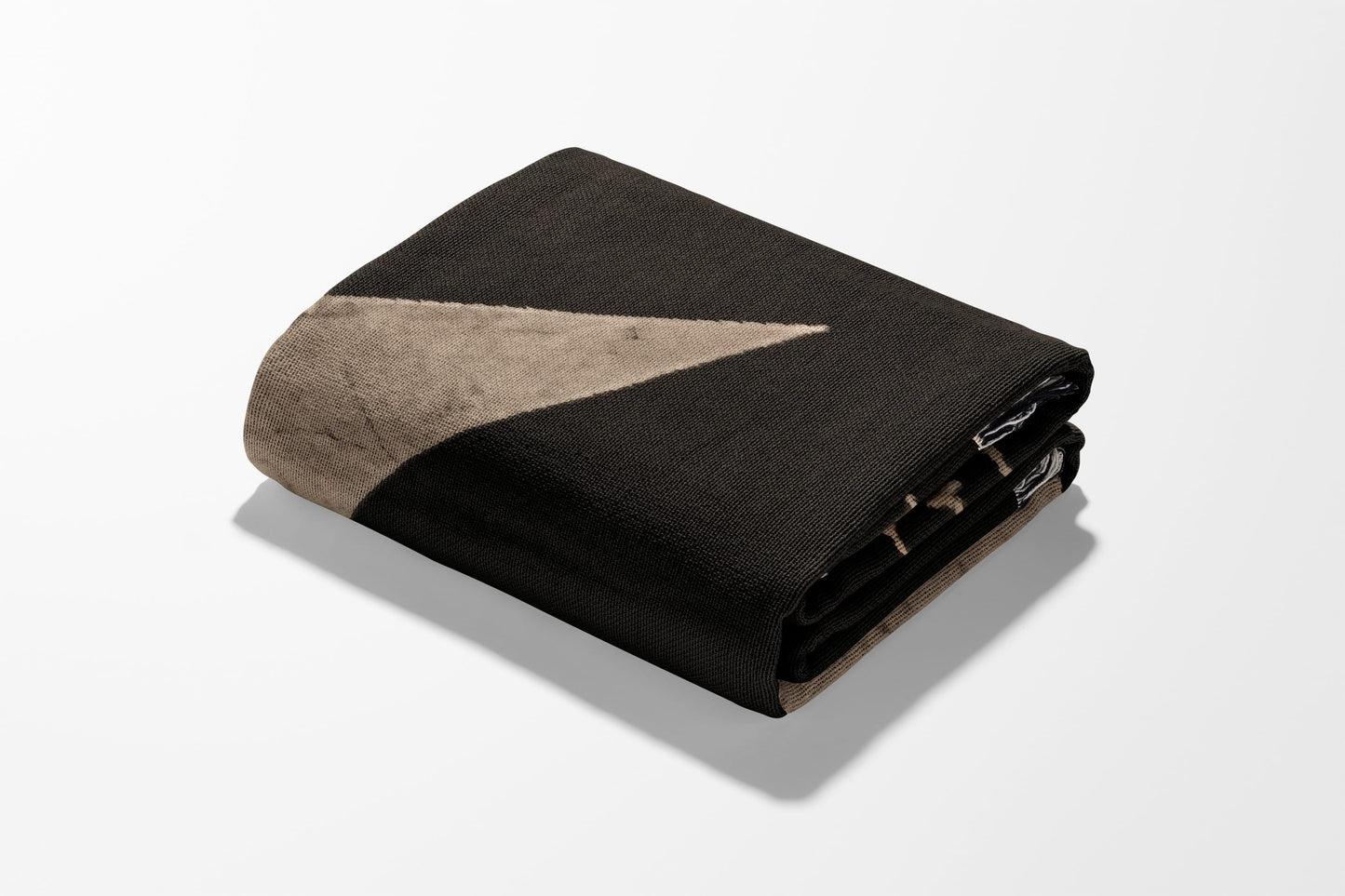 Folded blanket with dark brown and beige geometric pattern.