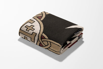 Folded blanket with intricate geometric and knotwork pattern.