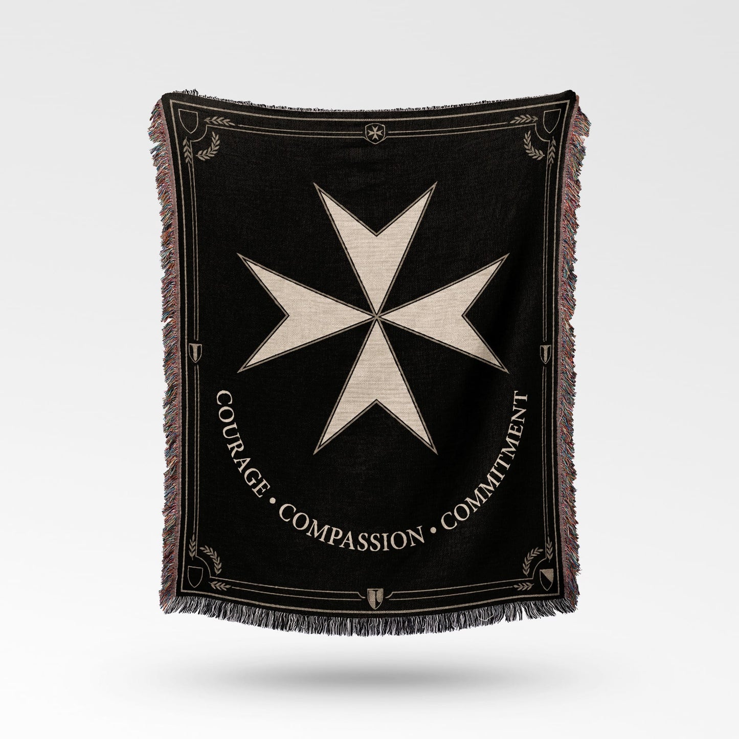 Black woven blanket with a Maltese cross emblem and text "COURAGE COMPASSION COMMITMENT".