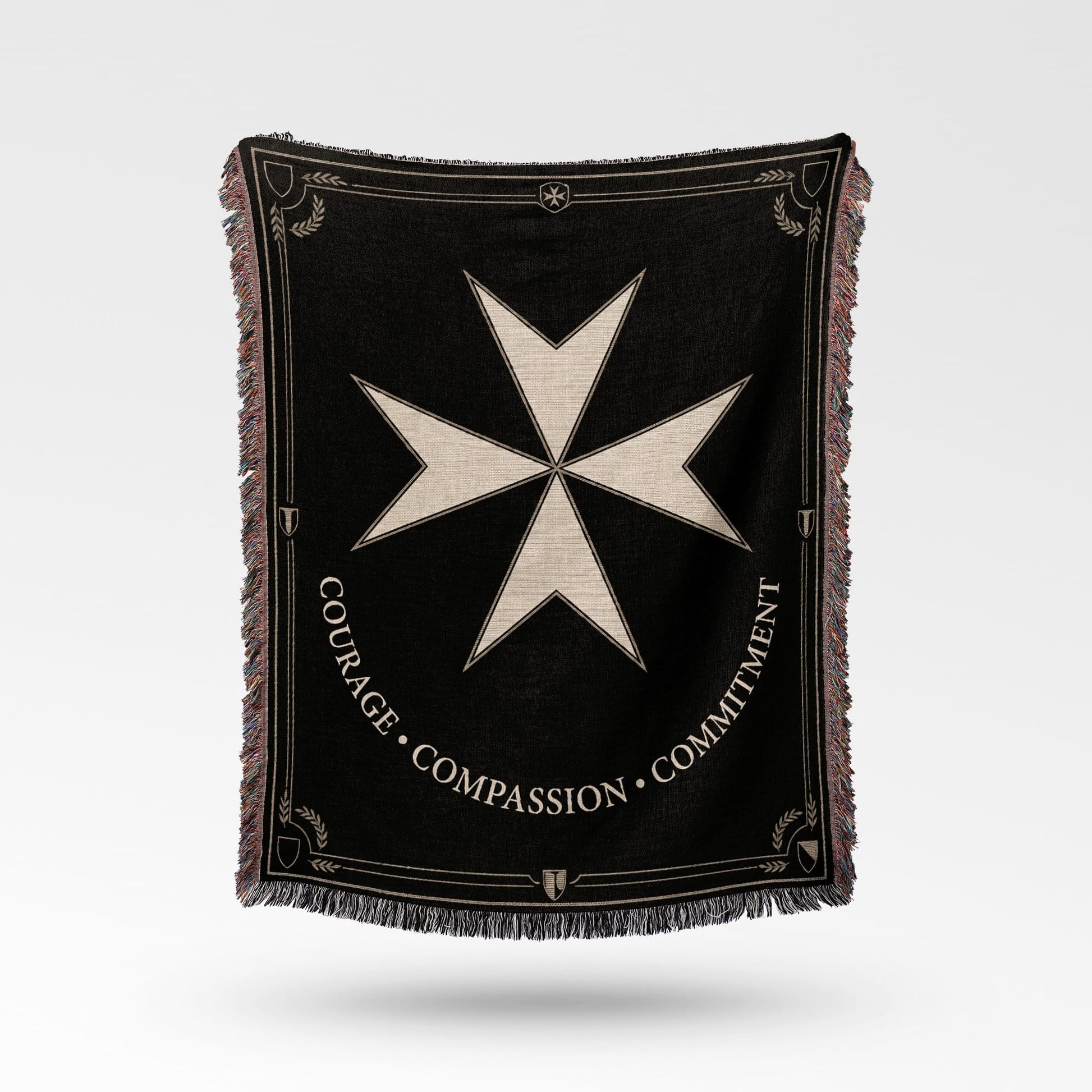 Black woven blanket with a Maltese cross emblem and text "COURAGE COMPASSION COMMITMENT".