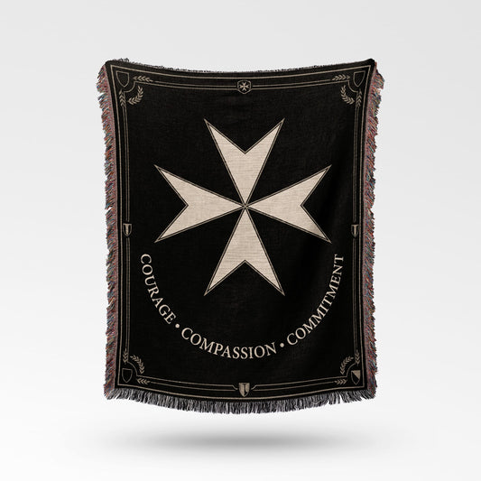 Black woven blanket with a Maltese cross emblem and text "COURAGE COMPASSION COMMITMENT".