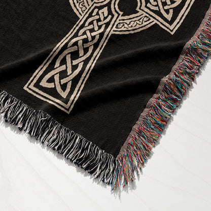 Black woven throw blanket with intricate beige Celtic knot design and fringed edge.