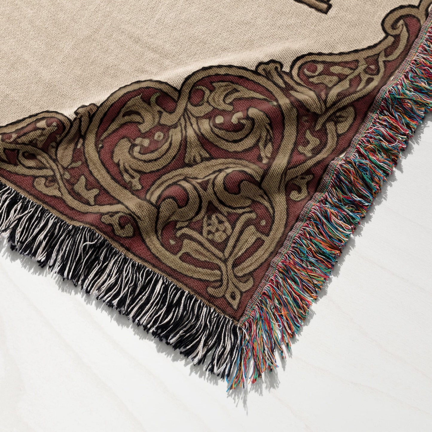 Woven throw blanket with ornate medieval-style pattern and multicolored fringe.