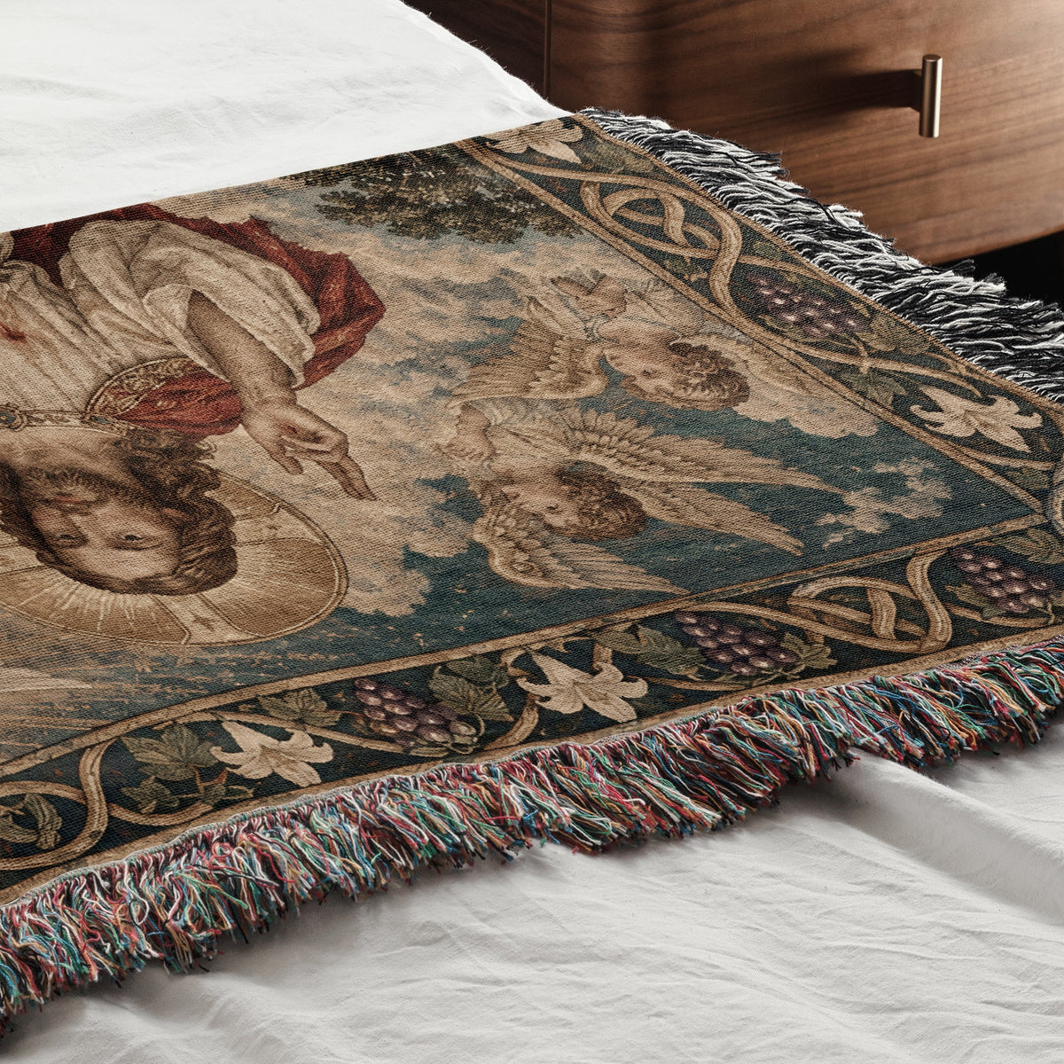 A woven throw blanket with a religious tapestry design featuring Jesus and angels lies on a bed.