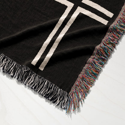 Black throw blanket with cream stripes and colorful fringe.