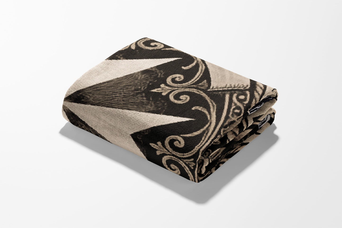 Folded blanket with black, beige geometric and scroll pattern on white background.