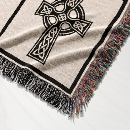 Woven throw blanket with a black Celtic cross design and multicolored fringed edges.