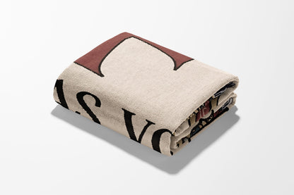 Folded cream-colored blanket with bold black and red text.