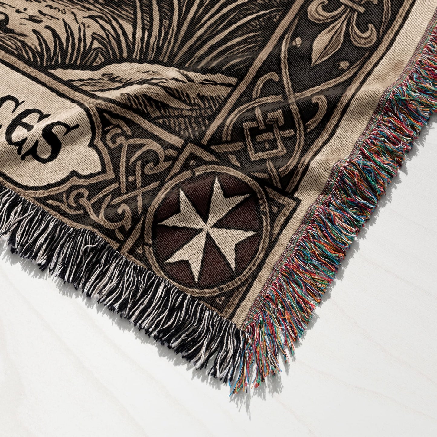 Woven blanket corner with Maltese cross and decorative border.