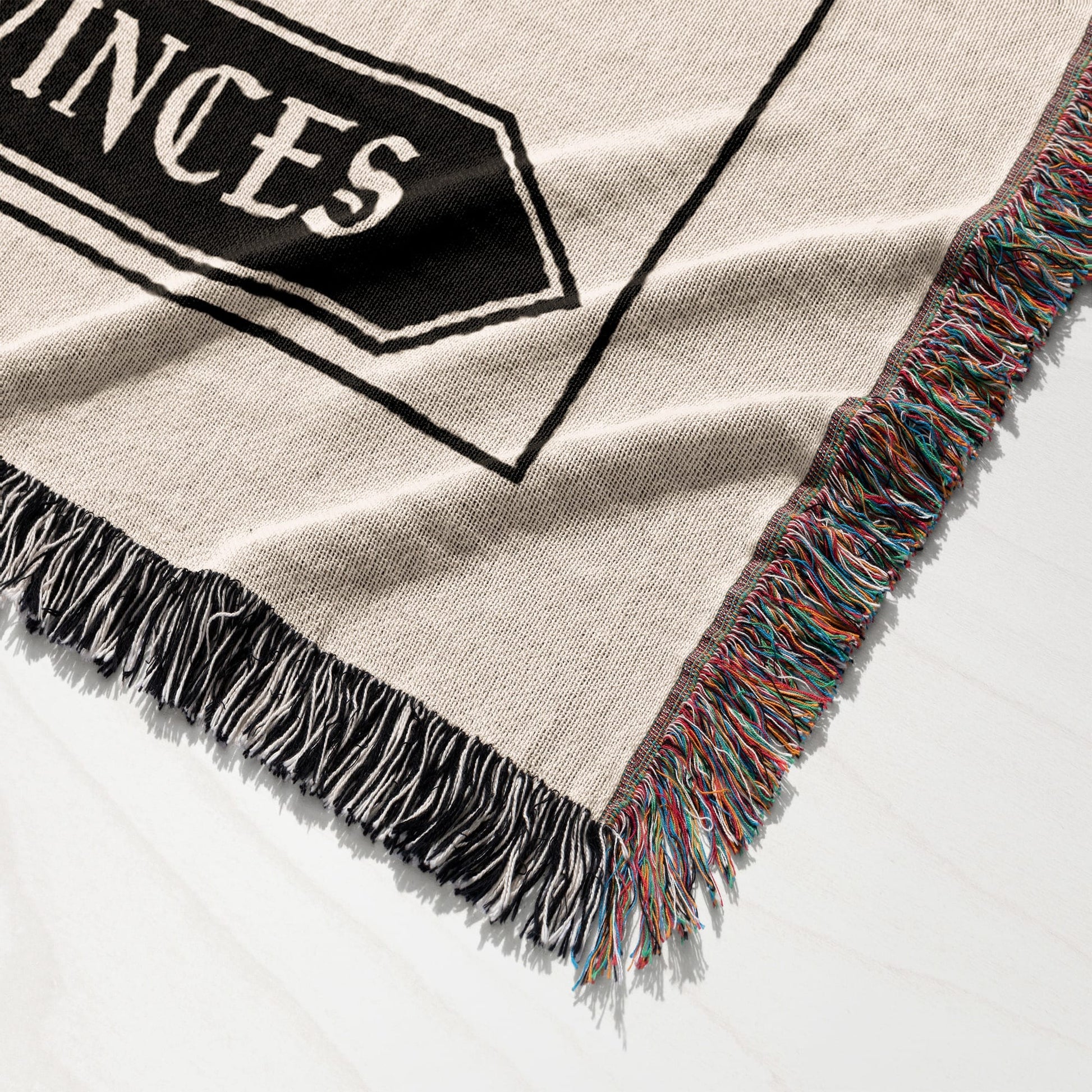 Woven blanket with black and white text and colorful fringed edges.