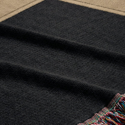 Textured black blanket with colorful fringe trim.
