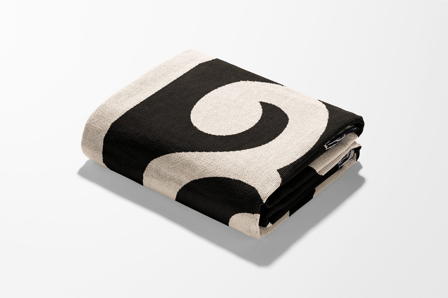 Black and cream patterned throw blanket folded on a white surface.