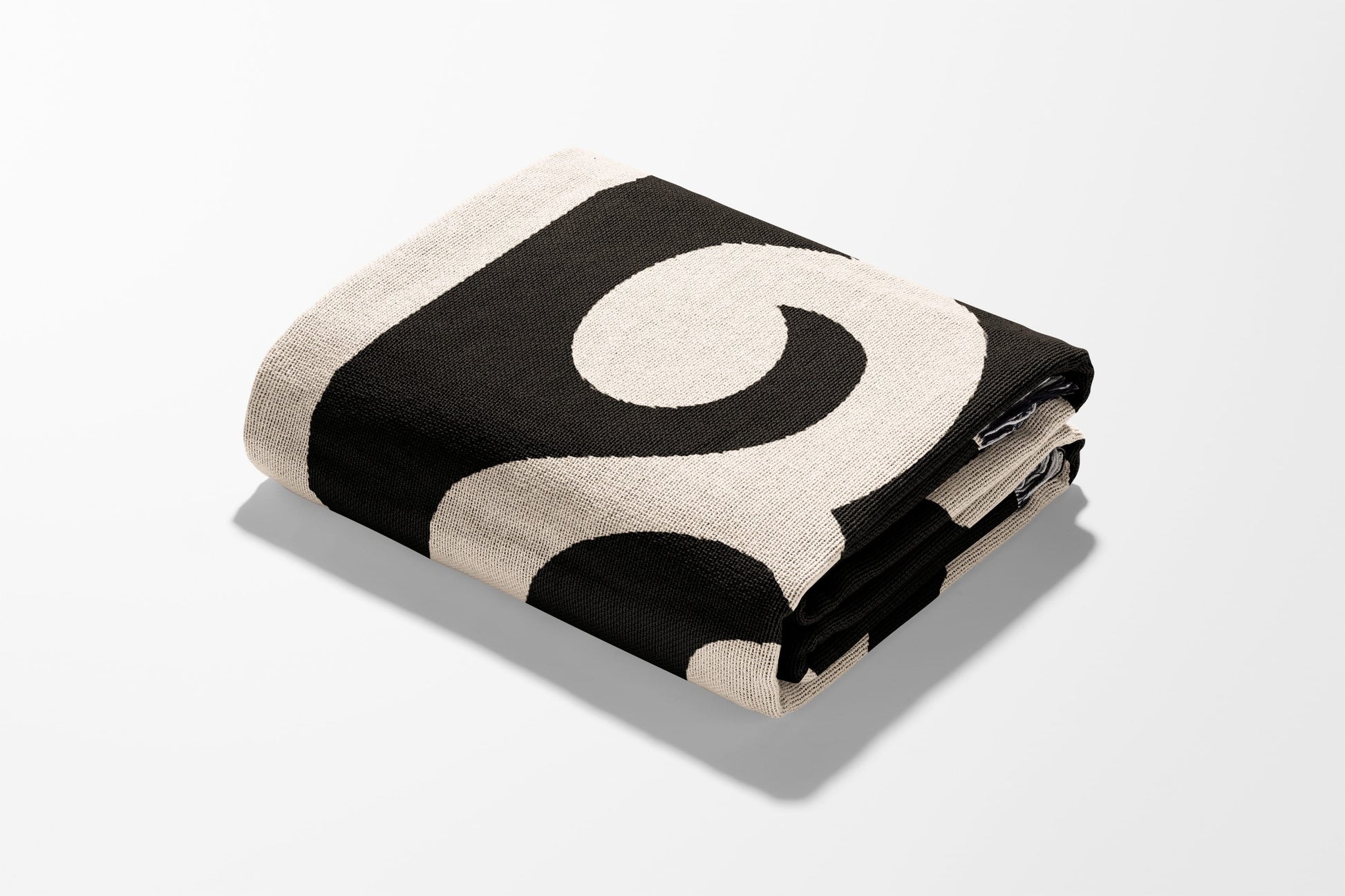 Black and cream patterned throw blanket folded on a white surface.