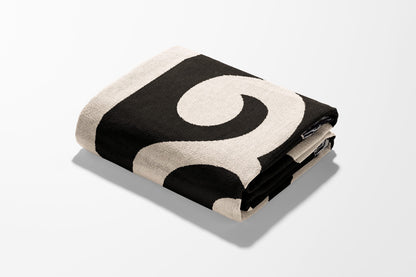 Black and cream patterned throw blanket folded on a white surface.
