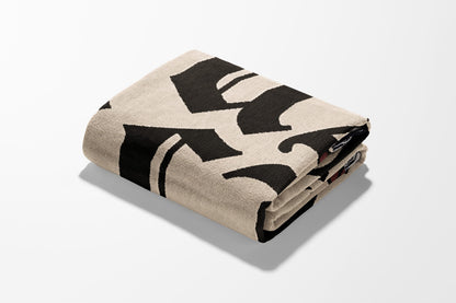Folded beige blanket with bold black gothic lettering.