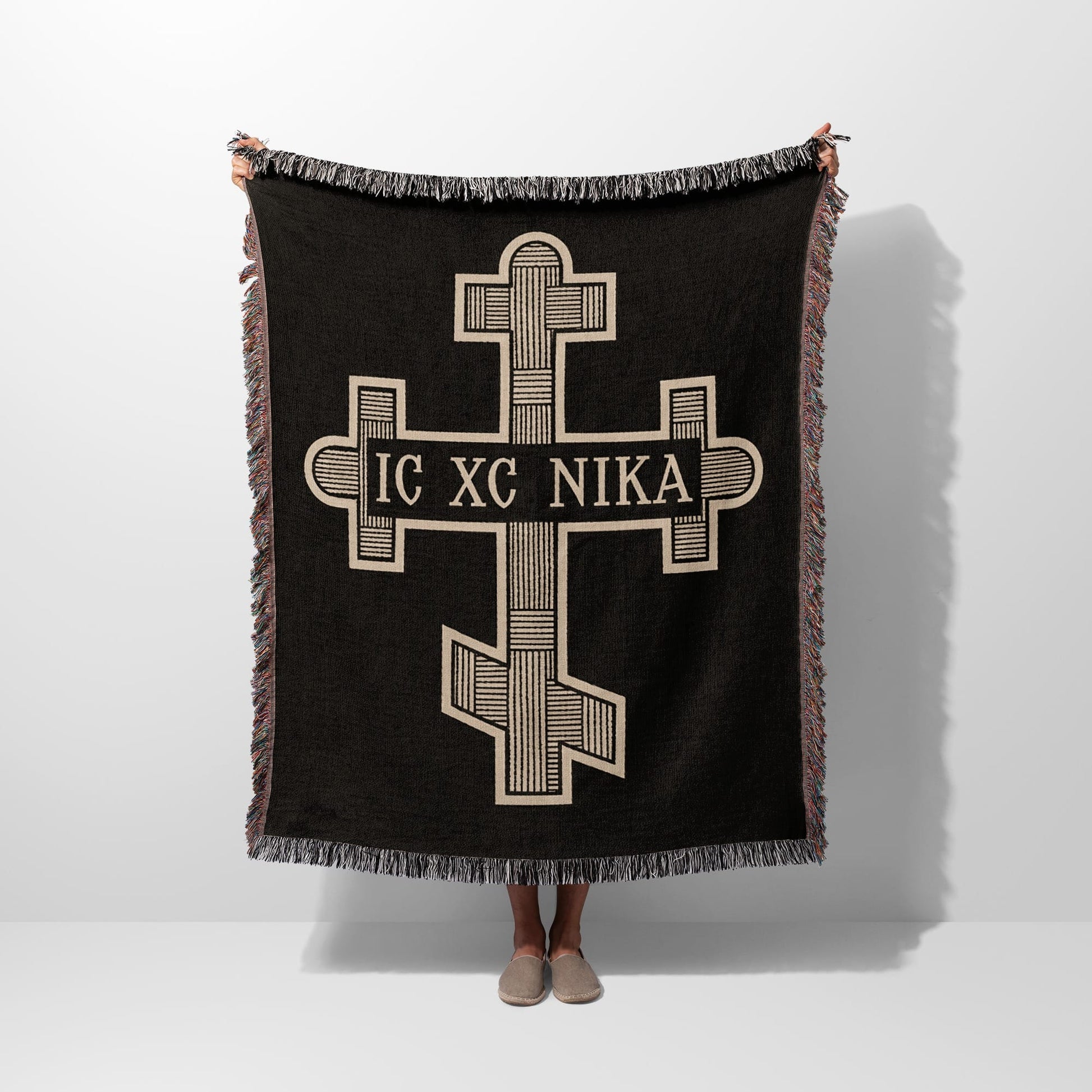 Black throw blanket with a cream-colored orthodox cross and text IC XC NIKA.