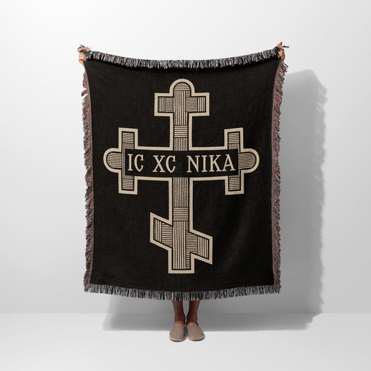 Black throw blanket with a cream-colored orthodox cross and text IC XC NIKA.