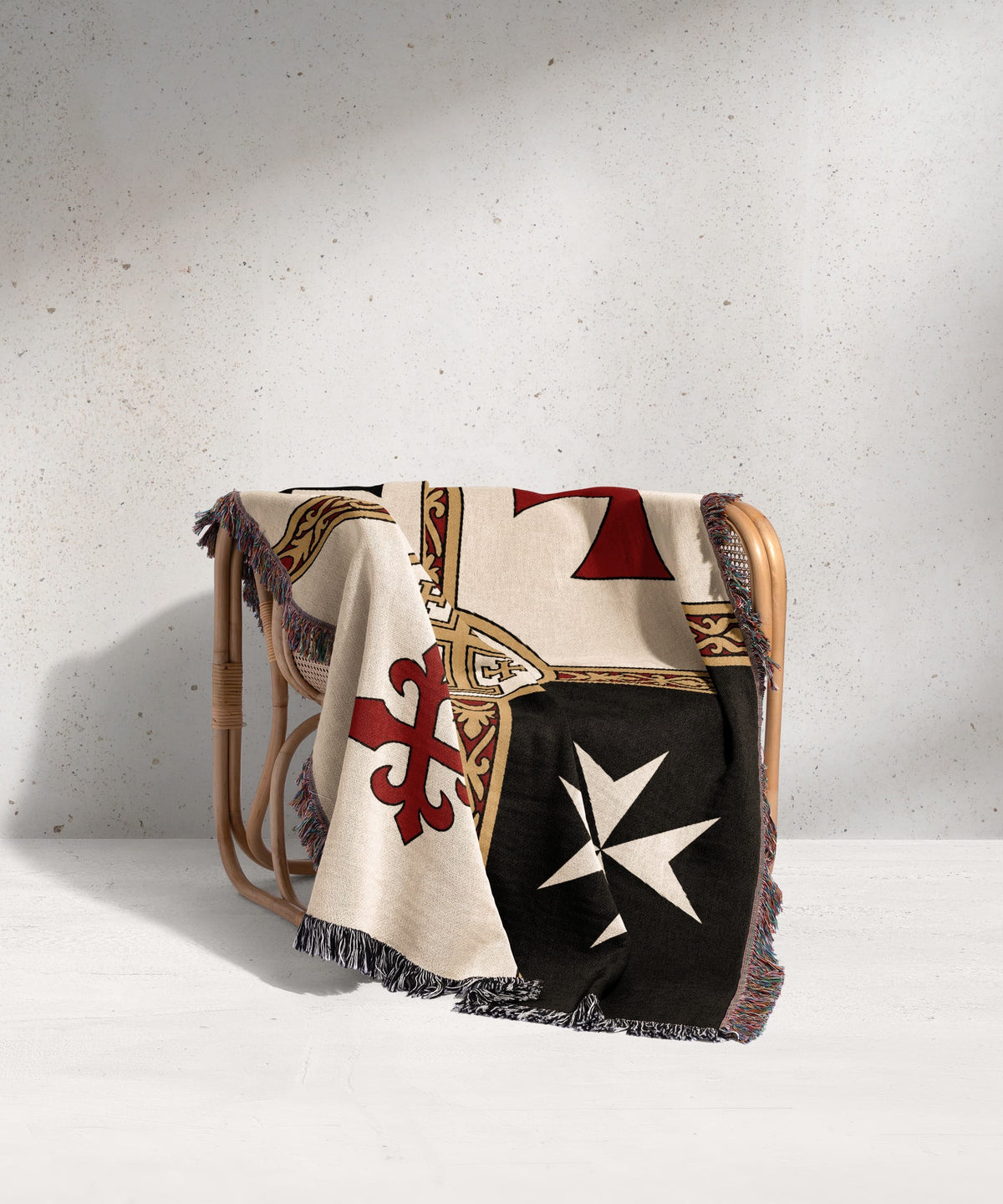 Woven blanket with white, black, red, and gold Maltese cross patterns draped over chair.