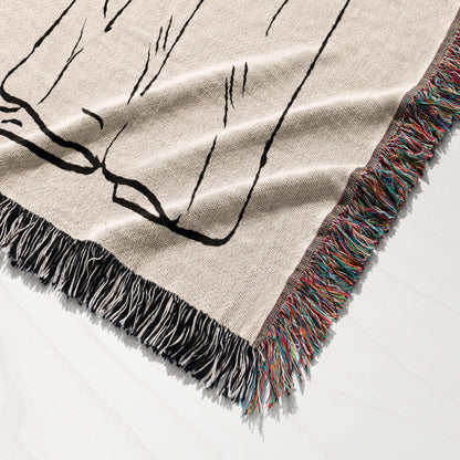 Woven blanket with fringe and black line drawing of glasses.