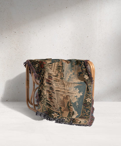 A patterned woven throw blanket draped over a light wood rattan armchair.
