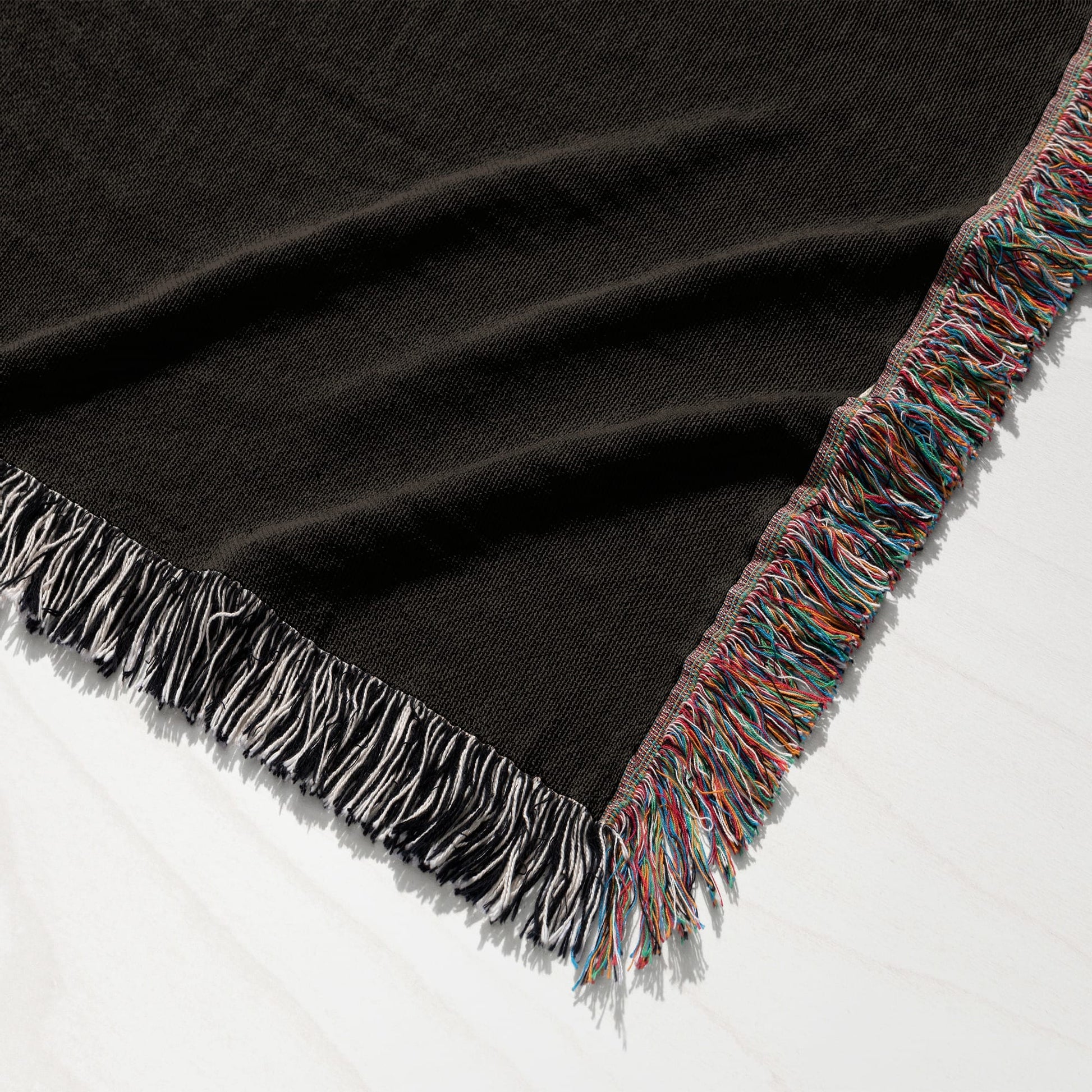 Dark brown woven throw blanket with colorful fringe.