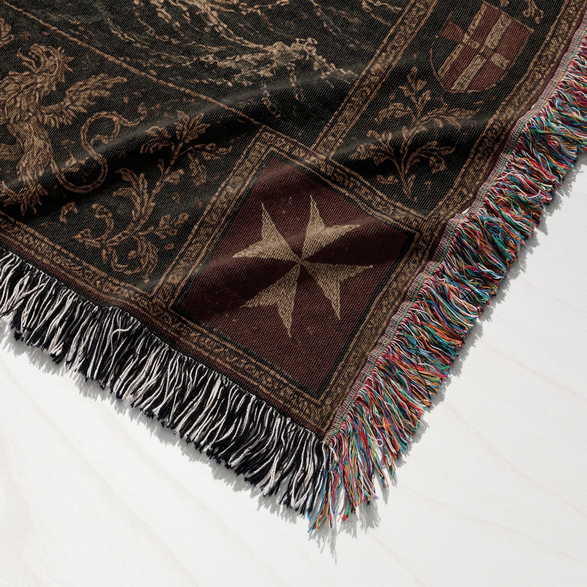 Black woven throw blanket with a Maltese cross and intricate pattern, fringed edges.