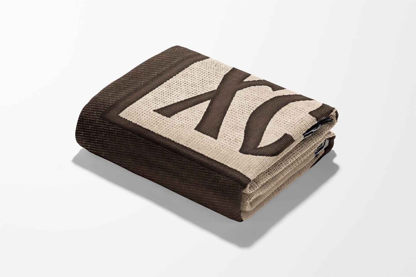 Folded brown blanket with large cream "XC" pattern and dark brown border.
