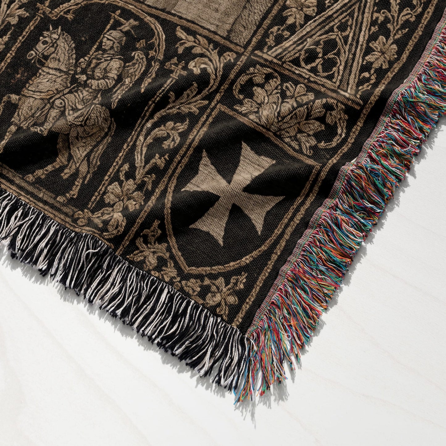 Black tapestry blanket with medieval knights and a cross, fringed edges.