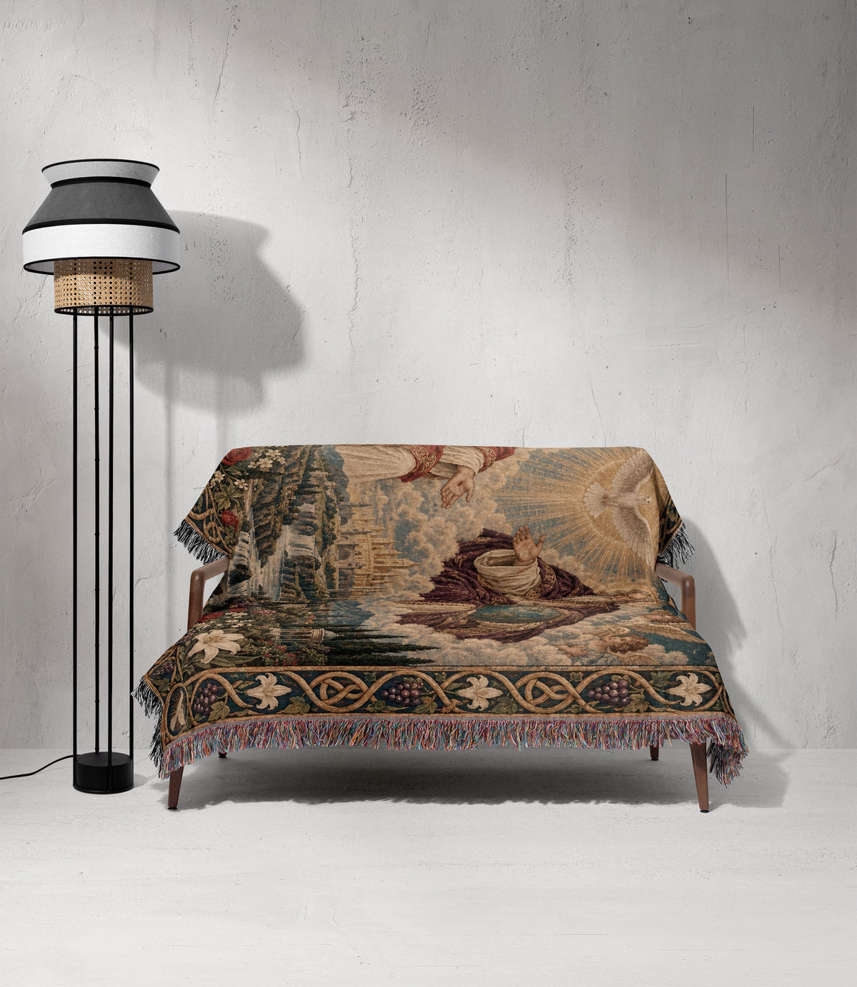 A wooden frame sofa is covered with a fringed woven throw blanket depicting a religious scene.