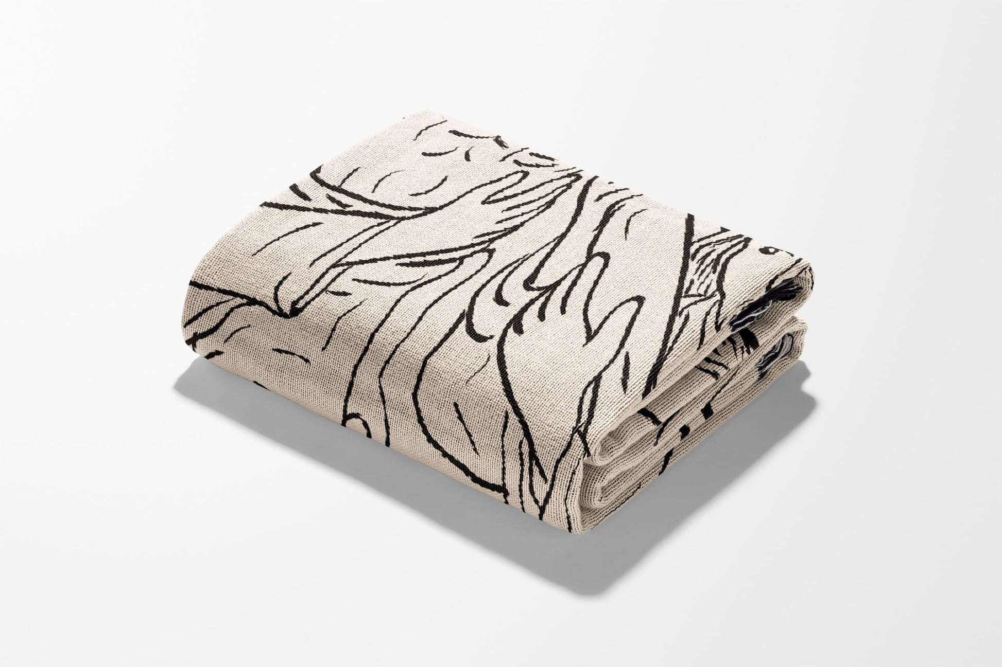 Folded blanket with abstract black line art pattern on cream background.
