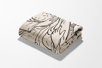 Folded blanket with abstract black line art pattern on cream background.