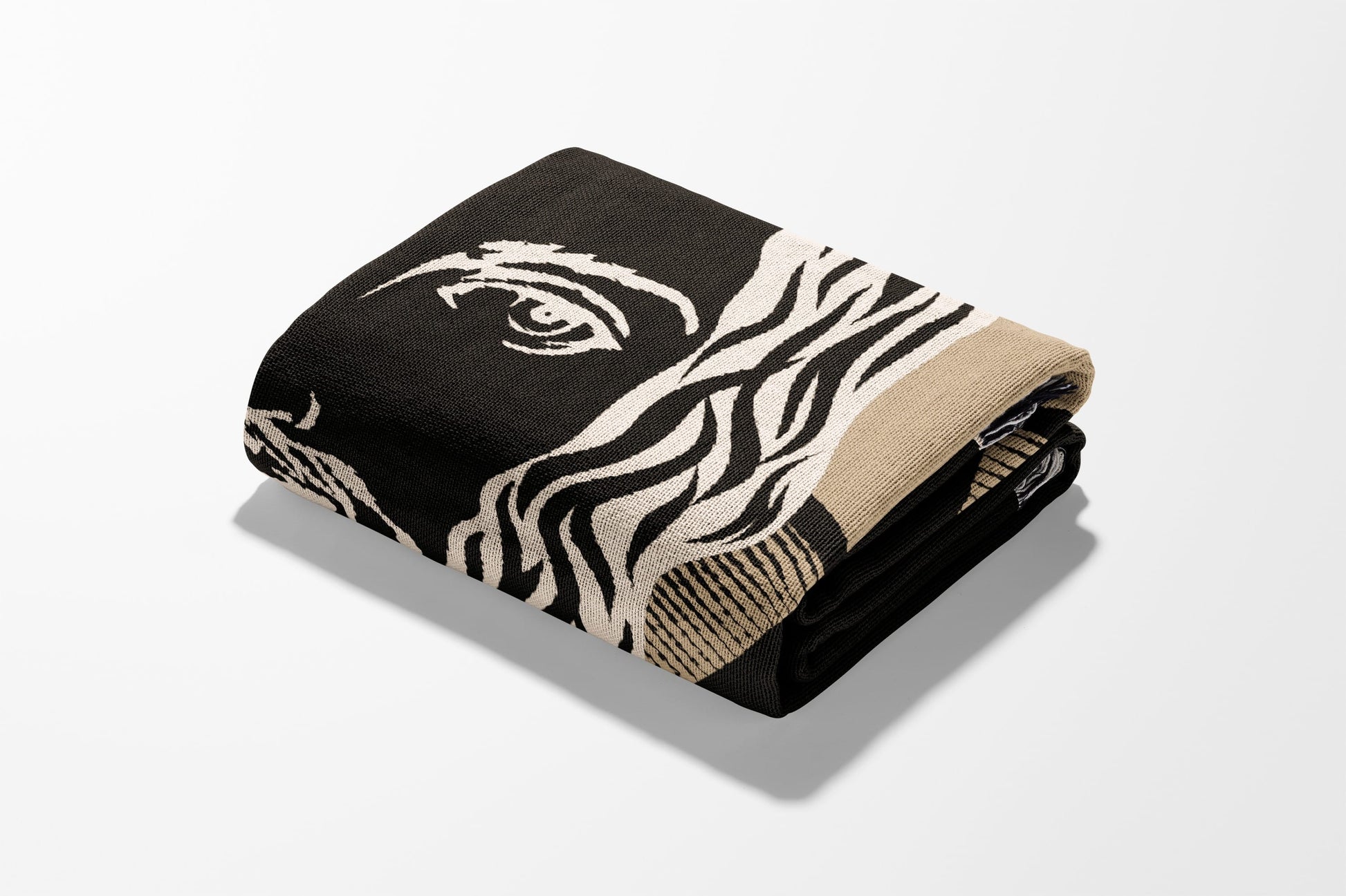 Black and beige blanket with a zebra eye pattern, folded.