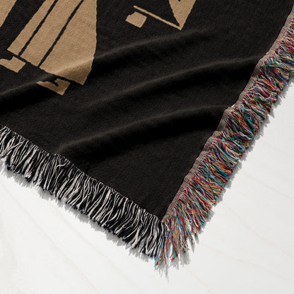 Black throw blanket with colorful fringed edges and a large tan geometric design.