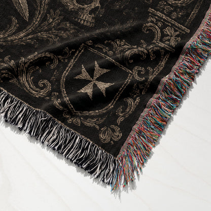 Black blanket with medieval design, shield, and skull motifs, fringed edges.