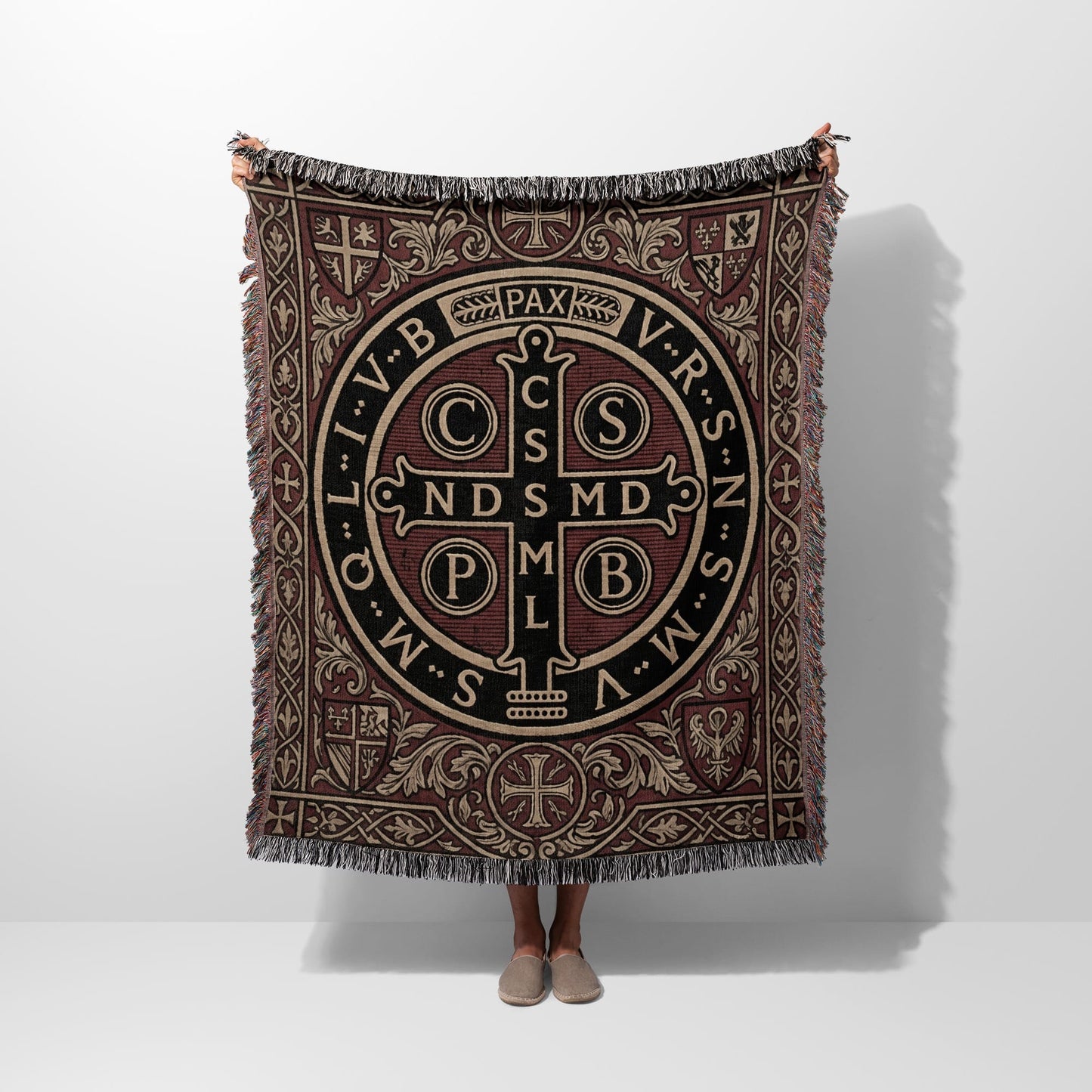 Tapestry blanket with Saint Benedict medal design and fringe trim.