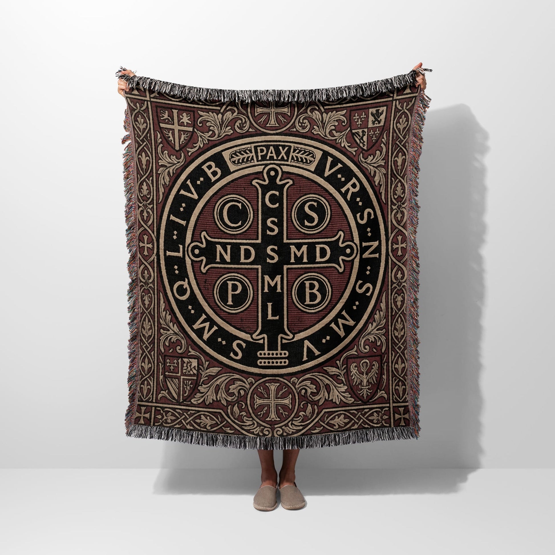 Tapestry blanket with Saint Benedict medal design and fringe trim.