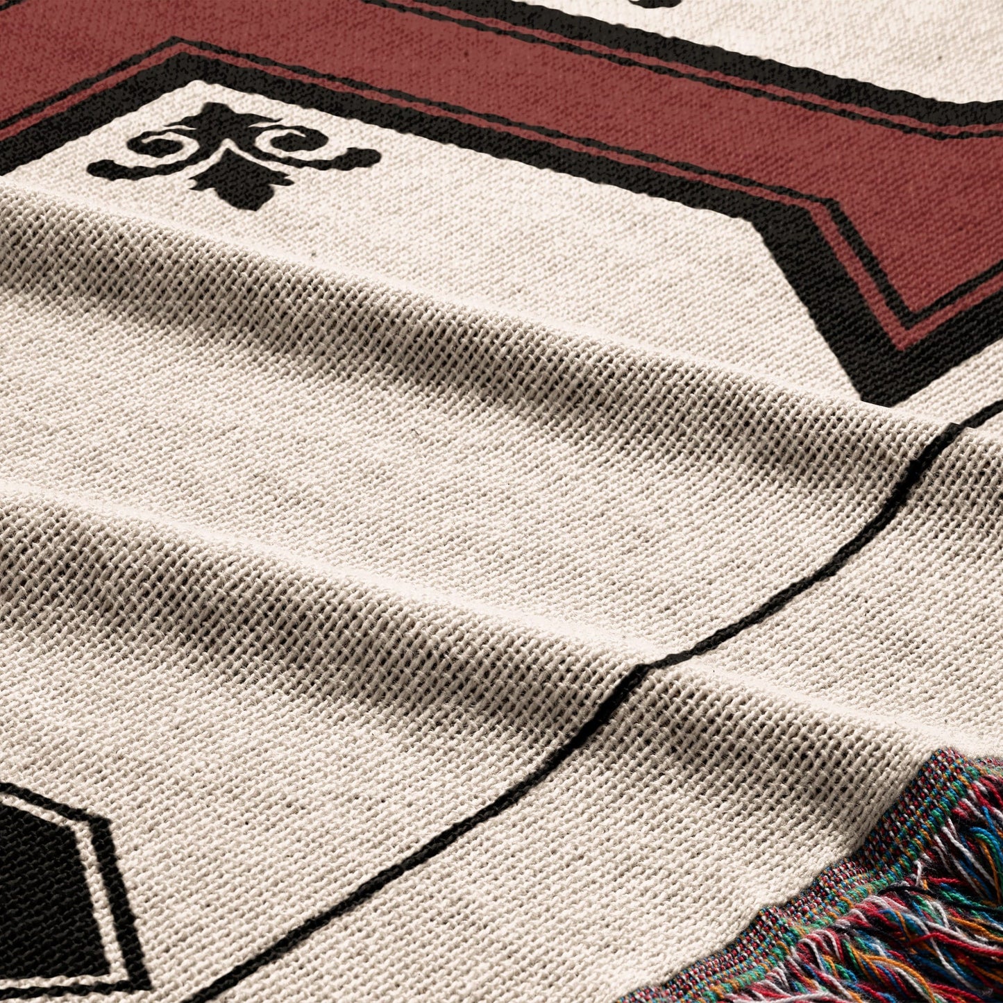 Woven throw blanket with geometric pattern and fringed edge in red and black.
