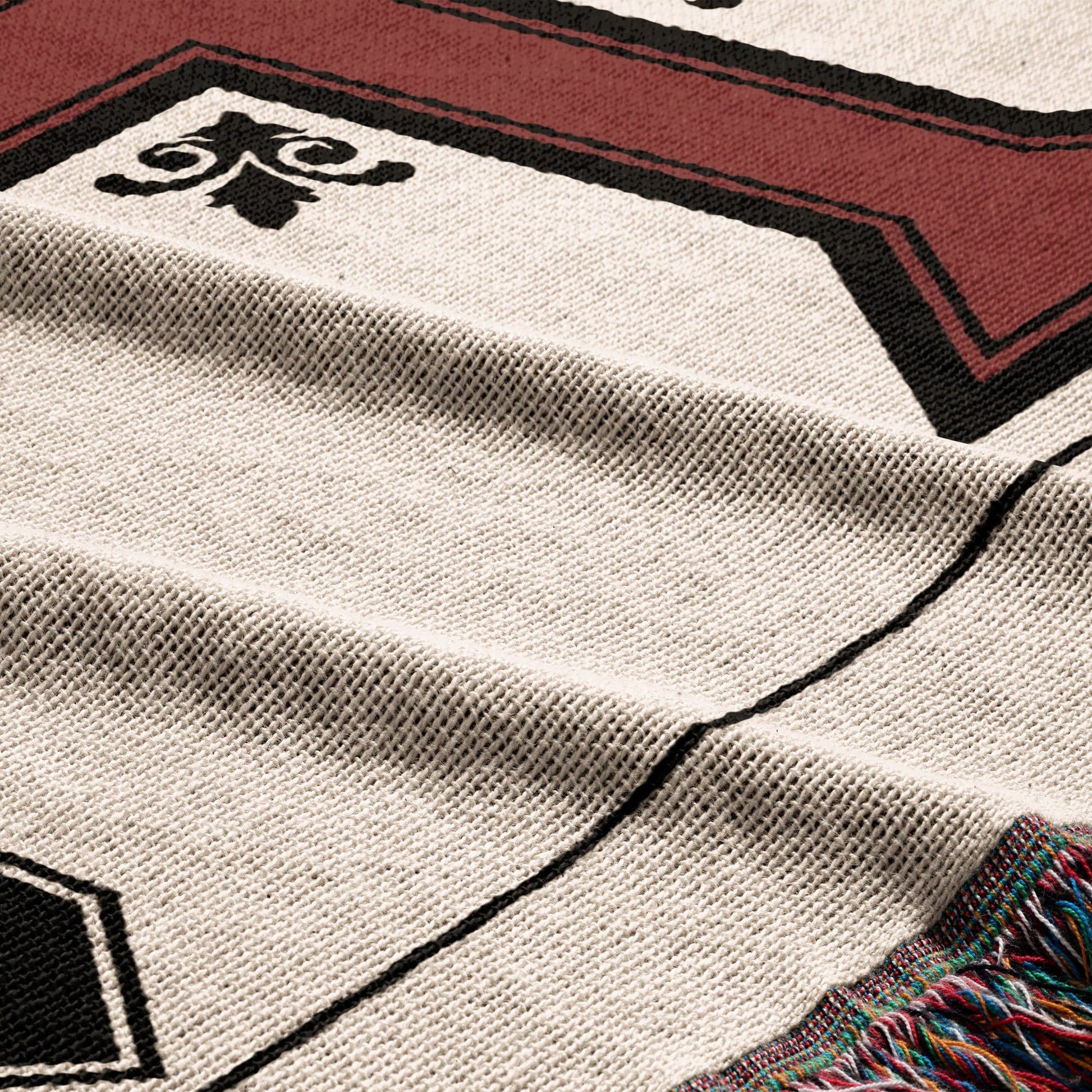 Woven throw blanket with geometric pattern and fringed edge in red and black.