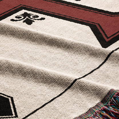 Woven throw blanket with geometric pattern and fringed edge in red and black.