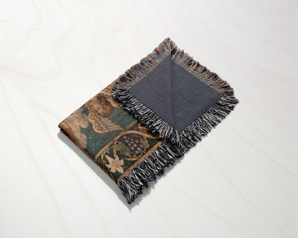 A folded woven blanket with a decorative nature pattern and fringed edges on a light surface.